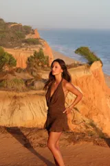 Vestido corto bordó con hilo brillante, escote halter pronunciado y detalle drapeado en el frente. Falda ajustada con fruncidos laterales y terminación con volados.