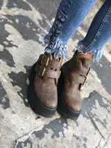 Botas cortas de cuero color marrón con suela de goma negra y plataforma. Presentan dos correas con hebillas doradas en el empeine.