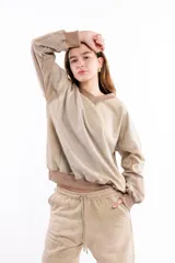 Buzo de algodón y cáñamo color beige con efecto lavado, escote en V y diseño con cortes estructurales en cuerpo y mangas. Presenta puños y cintura tejidos en tono contrastante.