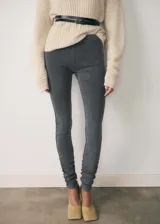 Pantalón ajustado tipo legging de tiro alto, confeccionado en tejido elástico con acabado efecto gamuza en color gris oscuro. Presenta cintura elástica y detalle de fruncido en los bajos.
