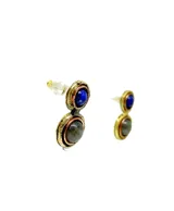 Caravanas artesanales de bronce con dos piedras naturales engarzadas en disposición vertical, una de color azul y otra gris. Presentan un acabado rústico con detalles circulares y cierre de presión.