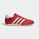 Championes Adidas modelo Taekwondo Lace, de estilo retro inspirado en artes marciales. Presentan un diseño en color rojo con las icónicas tres tiras laterales en blanco, puntera con acolchado 3D y costuras en contraste. Cuentan con suela de caucho de perfil bajo.