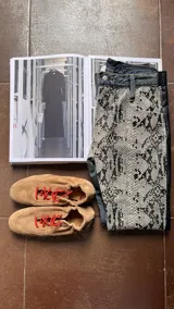 Pantalón de jean con paneles laterales de cuero con estampado de reptil. Presenta un diseño de corte recto y combinación de materiales.
