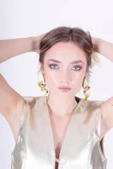 Aros colgantes dorados con forma de cinta rizada.