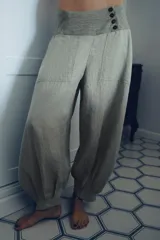 Pantalón bombacho de lino con tiro bajo, cintura ancha a contraste con cierre de botones, bolsillos laterales y bajo abullonado con puño.