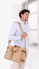 Mochila porta notebook color verde oliva de tela canvas con detalles en cuero marrón. Tiene múltiples bolsillos con cierre y correas ajustables.