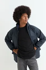 Campera de nylon color azul oscuro, con cierre frontal, capucha y bolsillos laterales con solapa. Presenta puños elásticos acanalados.