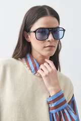 Chaleco tejido de punto con silueta relajada y diseño sin mangas. Presenta lazos laterales ajustables y cuello redondo.