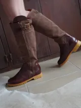 Botas altas de cuero marrón combinadas con gamuza blanca con estampado de vaca, forradas en cuero y con cierre de bronce.