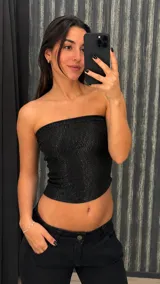 Top tipo palabra de honor confeccionado en tejido elástico negro con hilo de lurex brillante, de corte ajustado y diseño strapless.