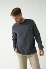 Remera de hombre color gris oscuro, de manga larga con puño, escote redondo y bolsillo en el pecho con etiqueta de marca.