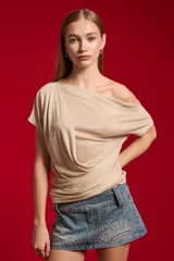 Top de poliéster con hilo Lúrex en color dorado, diseño al cuerpo con escote asimétrico y efecto drapeado.