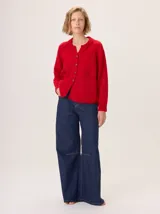 Saco de lana color marrón, de tejido grueso, con cuello redondo y botones frontales. Presenta mangas raglán con detalle de punto acanalado y bolsillos delanteros tipo parche.