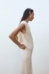 Top de punto color crema, de cuello redondo y sin mangas.