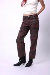 Pantalón de corte recto y largo al tobillo, con estampado geométrico en tonos oscuros y líneas rojizas. Posee tiro medio y cierre frontal.