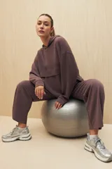 Canguro color marrón con capucha y diseño holgado, con detalle de recorte horizontal en el frente.