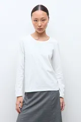 Remera de manga larga en color blanco, con cuello redondo y detalle de botones en los puños.