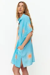 Túnica corta con estampado de soles y rayas verticales en contraste, con cuello camisero y mangas cortas.