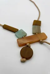 Collar largo de cordón beige con cuentas geométricas colgantes de piedra y madera en tonos marrón, naranja y celeste.