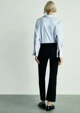 Jeans Alex de tiro medio confeccionados en denim negro, con diseño flare de corte acampanado y bajo deshilachado. Presenta cuatro bolsillos, incluyendo bolsillos frontales aplicados, y cierre frontal con cremallera y botón metálico.
