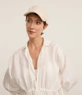 Gorra de aba curva en color beige, confeccionada en tejido de lino y viscosa con textura rústica y ajuste trasero con hebilla.