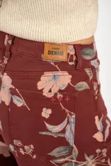 Jean de corte wide leg con tiro medio, confeccionado en algodón peinado. Presenta un diseño estampado con motivos florales sobre una base de color bordó.