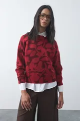 Sweater de punto con diseño estampado de hojas en tonos azul claro y azul oscuro. Presenta cuello redondo, mangas largas y terminaciones acanaladas en puños y ruedo.