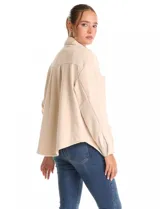 Sobrecamisa de pana color beige, con cuello solapa, cierre frontal con botones metálicos y bolsillos frontales amplios. Presenta una silueta holgada con hombros caídos y costuras estructuradas.