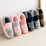 Pantuflas cerradas de color azul con diseño de gatito, confeccionadas en piel sintética suave con interior de peluche gris. Presentan un bordado con la frase 'Welcome Home' y apliques de patitas de gato. Cuentan con suela de goma antideslizante.