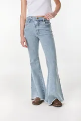 Pantalón jean de corte acampanado y tiro alto, color beige, con costuras visibles y terminación deshilachada en los tobillos.