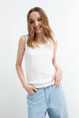 Top tejido de punto color blanco, sin mangas, con escote geométrico y corte al cuerpo.