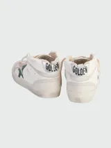 Championes de caña media Golden Goose Mid Star de cuero blanco con estrella verde y detalles desgastados.