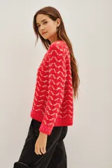 Sweater de punto con diseño de patrón geométrico en colores rojo y blanco, cuello redondo y mangas largas.