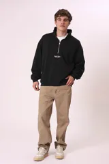 Sudadera negra con cierre de cremallera metálica en el cuello y estampado con texto en el pecho.