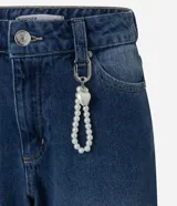 Pantalón baggy de jean azul con tiro medio, corte holgado, recortes en las rodillas y llavero decorativo con perlas y dije de corazón.