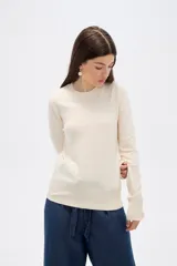 Sweater de lyocell al cuerpo, con cuello redondo a la base y mangas largas con detalle de botones en los puños.