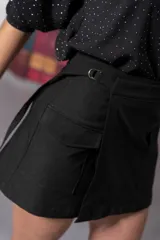 Pollera short negra con corte irregular y bolsillos delanteros con solapa.