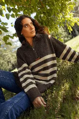 Buzo de lana merino con diseño a rayas horizontales en tonos marrón y beige, cuello alto con cierre frontal parcial y detalle de parche de cuero en el pecho.