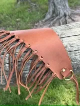 Faja ancha de cuero vacuno en color marrón, con diseño de flecos largos y cierre frontal con argollas metálicas y lazo ajustable.