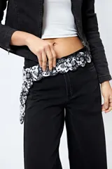 Cinturón negro con piezas circulares unidas y apliques metálicos plateados.