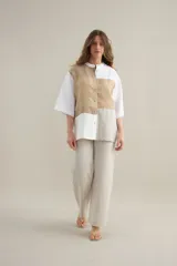 Camisa de lino de calce relajado, con cuello mao, mangas cortas y un diseño de bloques de color en tonos blanco, verde militar, tostado y negro. Cuenta con cierre frontal de botones.