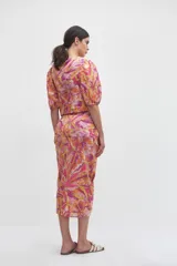 Blusa crop top rosada con estampado floral en tonos amarillos, naranjas y blancos, con escote en V, mangas abullonadas cortas y detalle de aro forrado en el centro del pecho con fruncidos.