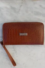 Billetera tipo sobre con correa de muñeca, confeccionada en cuero con textura de reptil en color marrón. Cuenta con cierre perimetral y placa metálica con el logo de la marca en el frente.