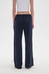 Pantalon deportivo de corte recto y tiro medio, color tostado, con cintura elástica y franjas laterales en tono más claro. Presenta aberturas en los tobillos con cordones ajustables.