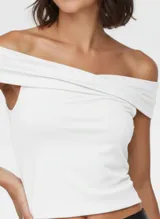 Top ajustado blanco con escote Bardot (off-shoulder) cruzado en el busto.