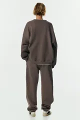 Pantalón deportivo de tiro alto confeccionado en felpa de mezcla de algodón con interior cepillado. Presenta cintura elástica con cordón de ajuste, bolsillos laterales al bies y puños elásticos en los bajos.