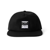 Gorro negro de cinco paneles con visera plana y parche bordado en el frente con diseño abstracto en blanco y negro.