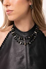 Collar corto de doble vuelta compuesto por cuentas de nácar, discos de piedra hematite en tonos dorados y plateados, y mostacillas negras. Incluye cadena de acero quirúrgico ajustable.