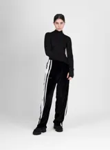 Pantalón de terciopelo negro de corte ancho, con cintura elástica y tres rayas blancas verticales en los laterales.