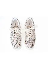 Championes bajos con capellada de pelo de cuero natural con estampado animal print tipo dálmata en tonos blanco y negro, suela plana de goma y cordones al tono.